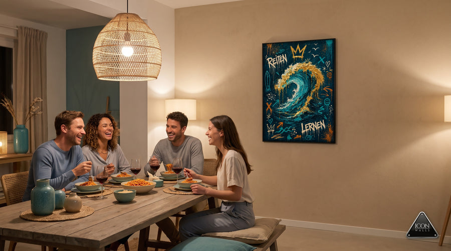 Vier Freunde lachen beim Abendessen im warm beleuchteten Esszimmer, an der Wand haengt das gerahmte Wellen-Poster Reiten Lernen in Tuerkis und Gold