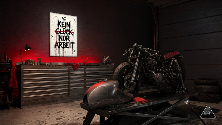 Schrauber-Garage mit Motorrad bei Nacht, Lichtfarbe Tiefes Crimson – an der Wand das Kunstwerk KEIN GLÜCK NUR ARBEIT