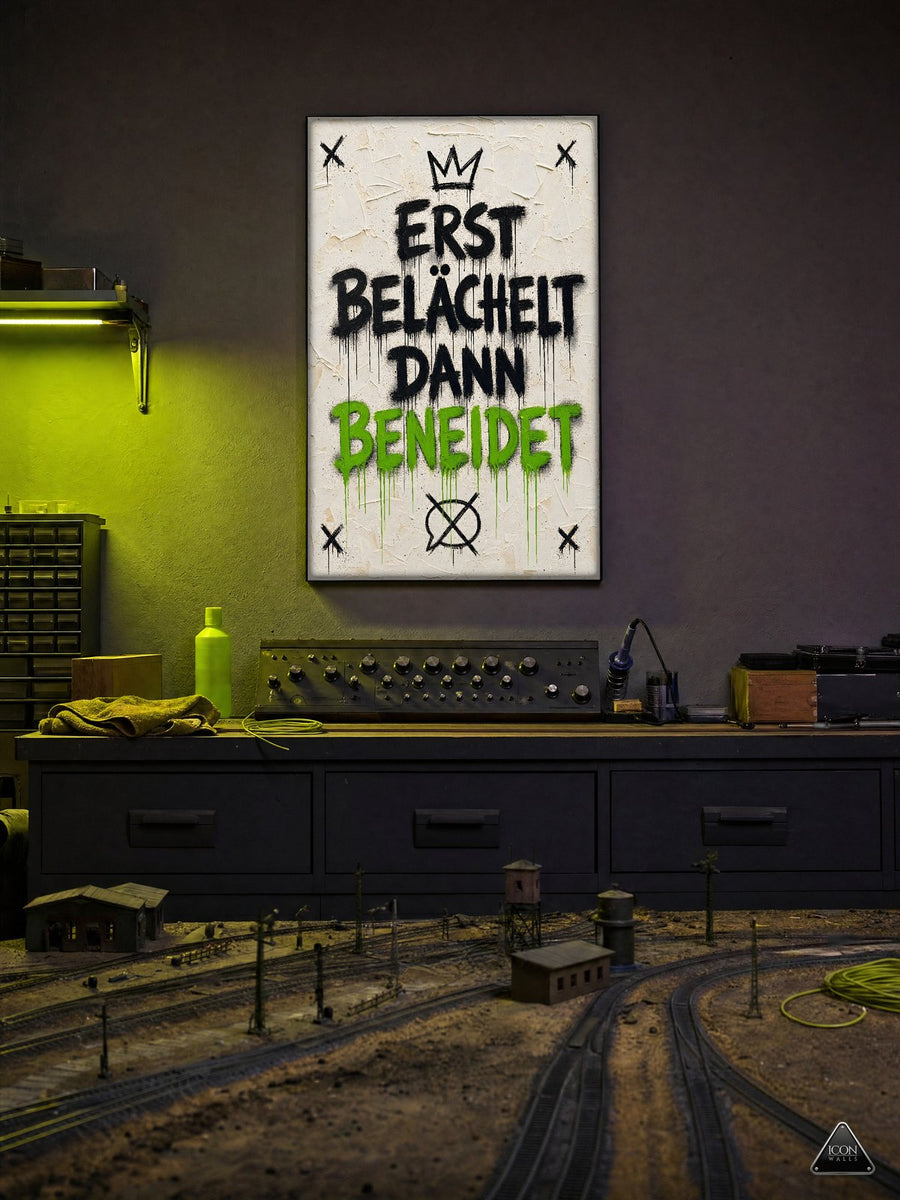 Modelleisenbahn im Hobbyzimmer bei Nacht, Lichtfarbe Giftiges Gelbgrün – an der Wand das Kunstwerk Erst belächelt, dann beneidet